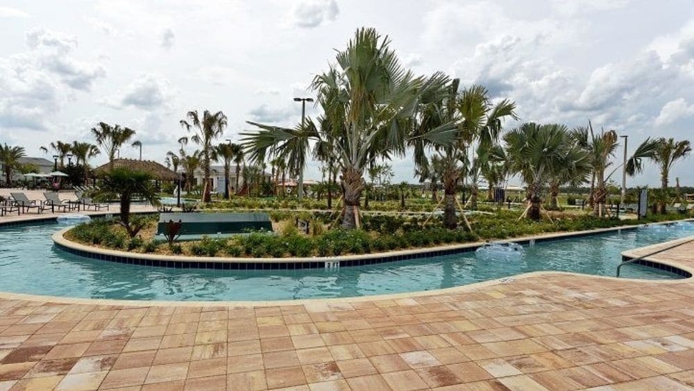 A small lazy river circling a man-made island of palm trees.