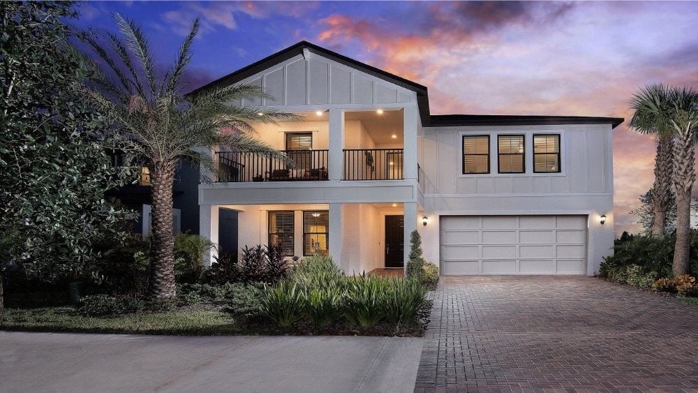 A modern two-story home with a manicured lawn and palm trees out front.