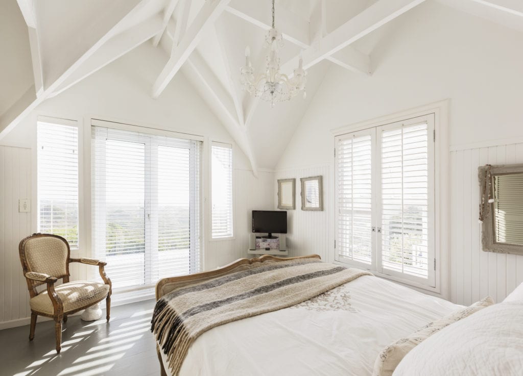 Modern, white luxury bedroom with vaulted ceilings, which add more light to the space.