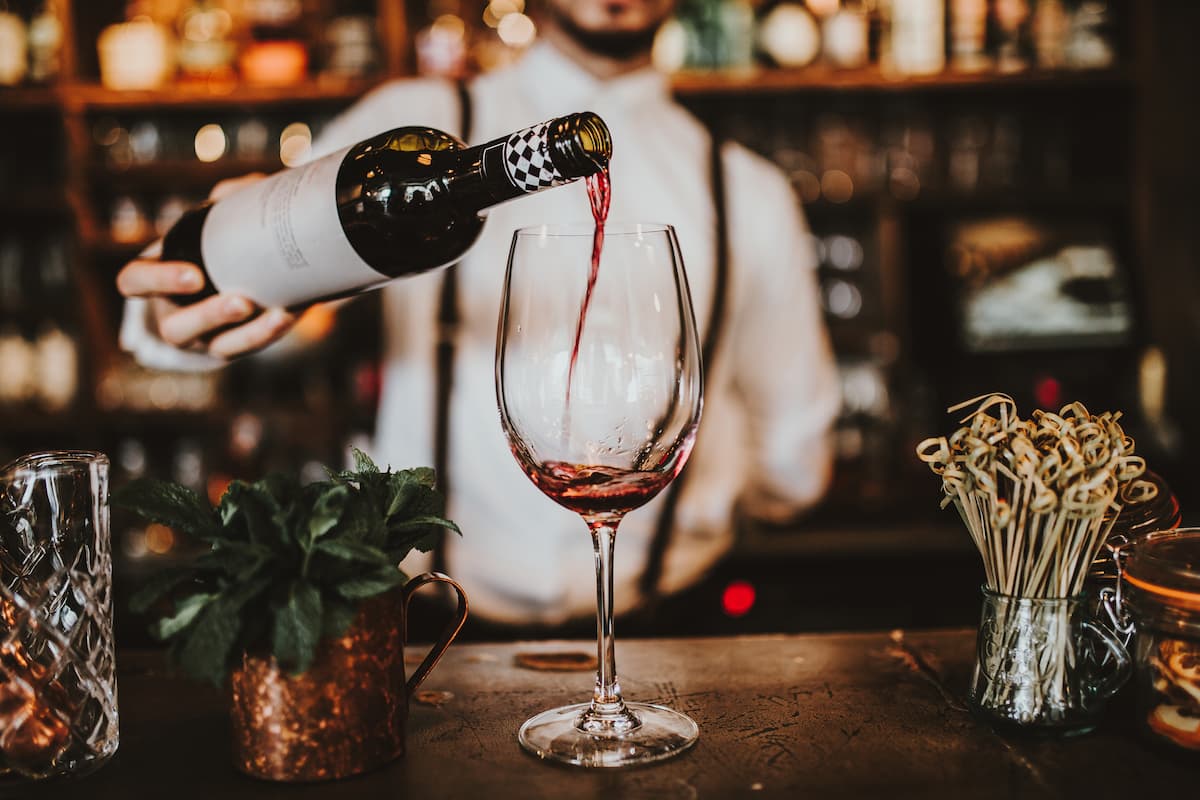 a glass of wine being poured by a bartender