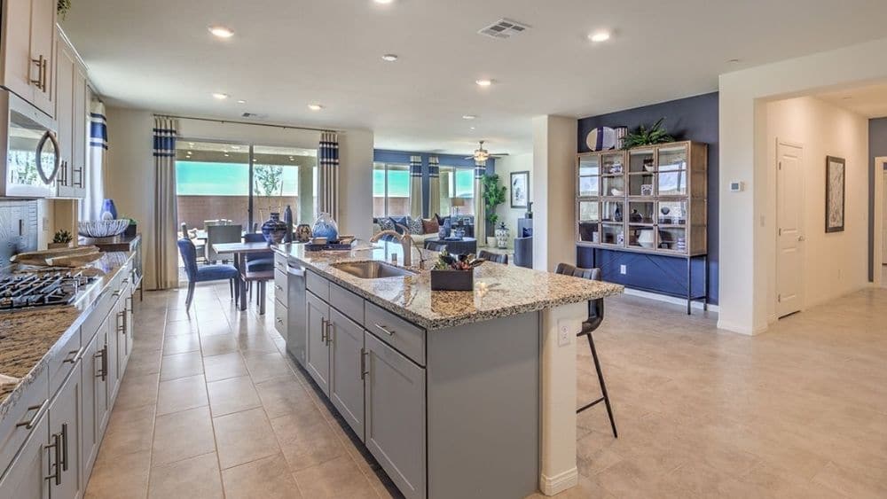 Fully furnished modern kitchen with granite counter tops and grey cabinetry.