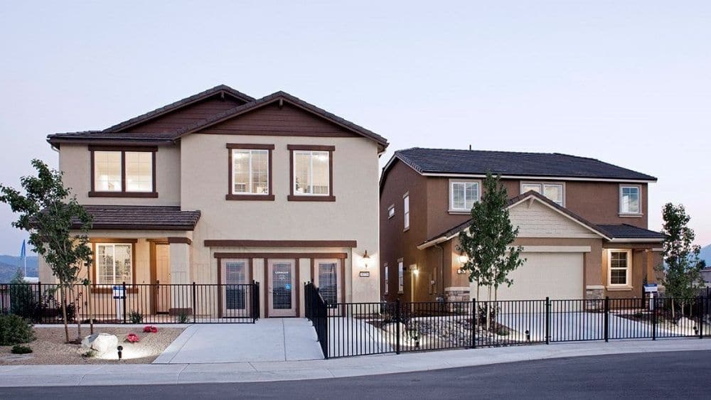 A two-story Spanish-style home with a sign indicating it is a model home.