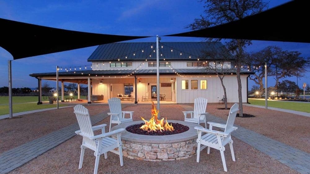 Chairs gathered around a fire pit with lights and awnings hanging above.