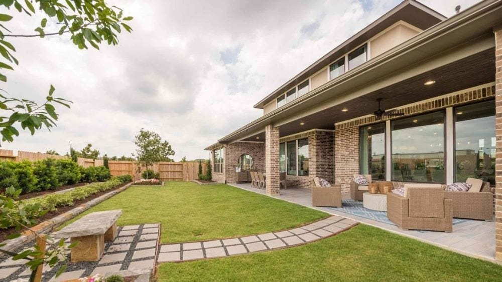Backyard of a modern home with lots of windows and a stone path through the yard.