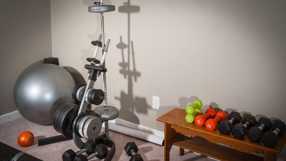 A dumbbell rack, exercise machine, and silver pilates ball.