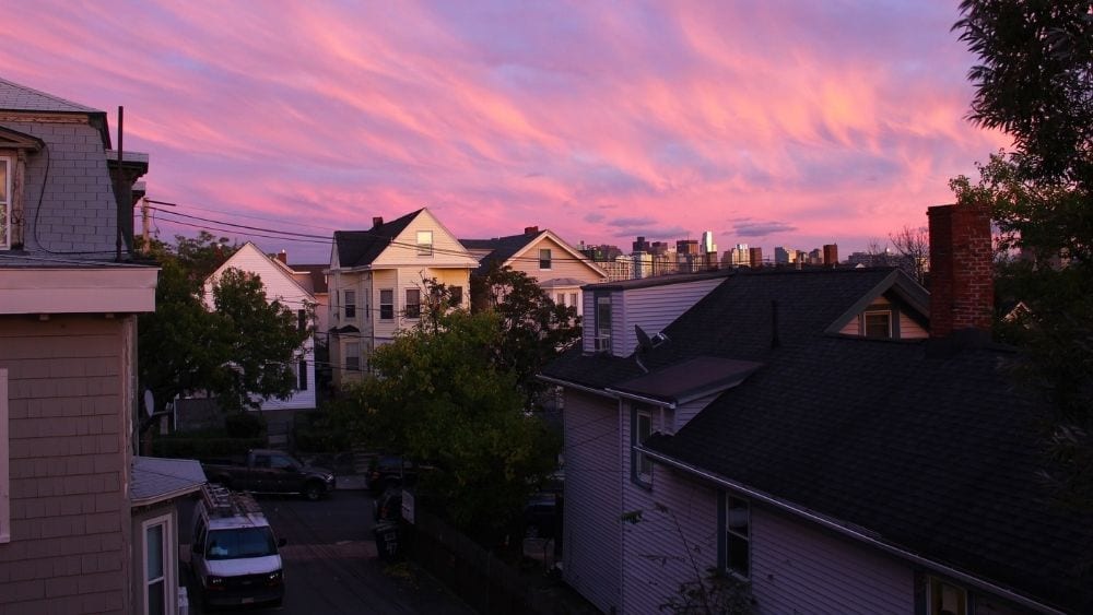 A pink and purple sky over suburban houses.