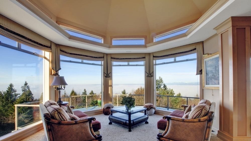 A sitting room with a cathedral ceiling and large bay windows.