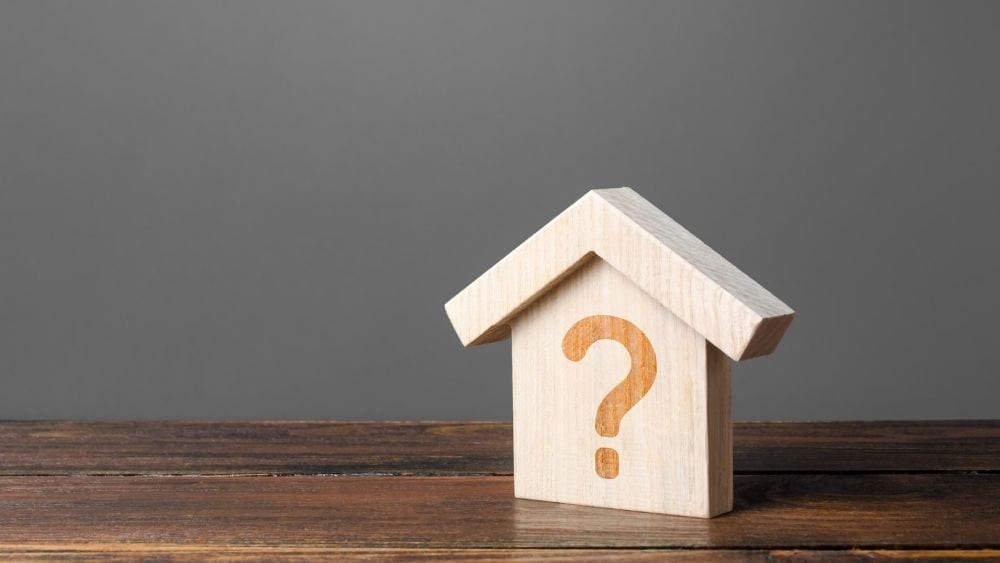 Small wooden house with a question mark painted on it.