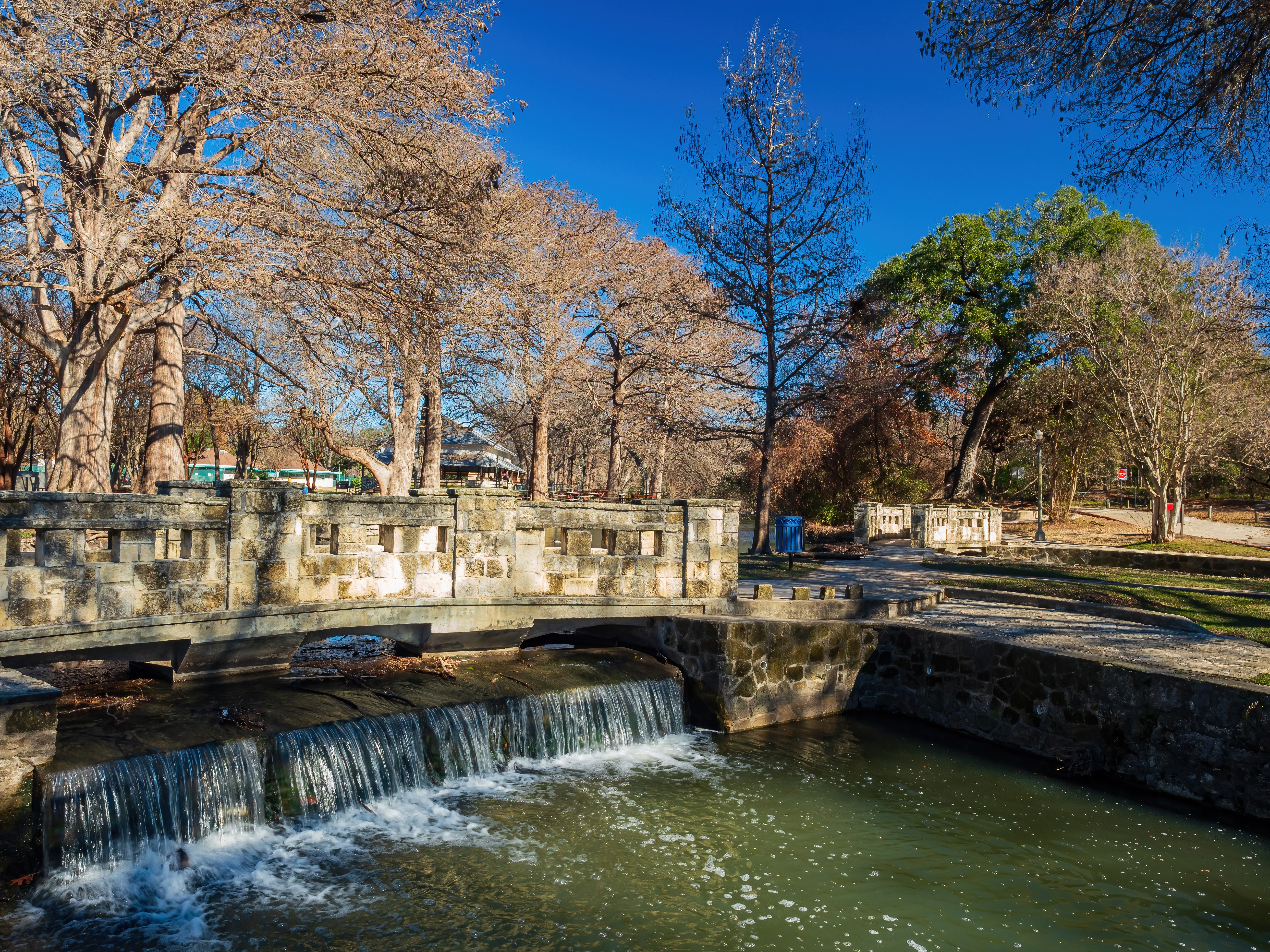 Flowing waterfall in treed park with walking trails and rock walls