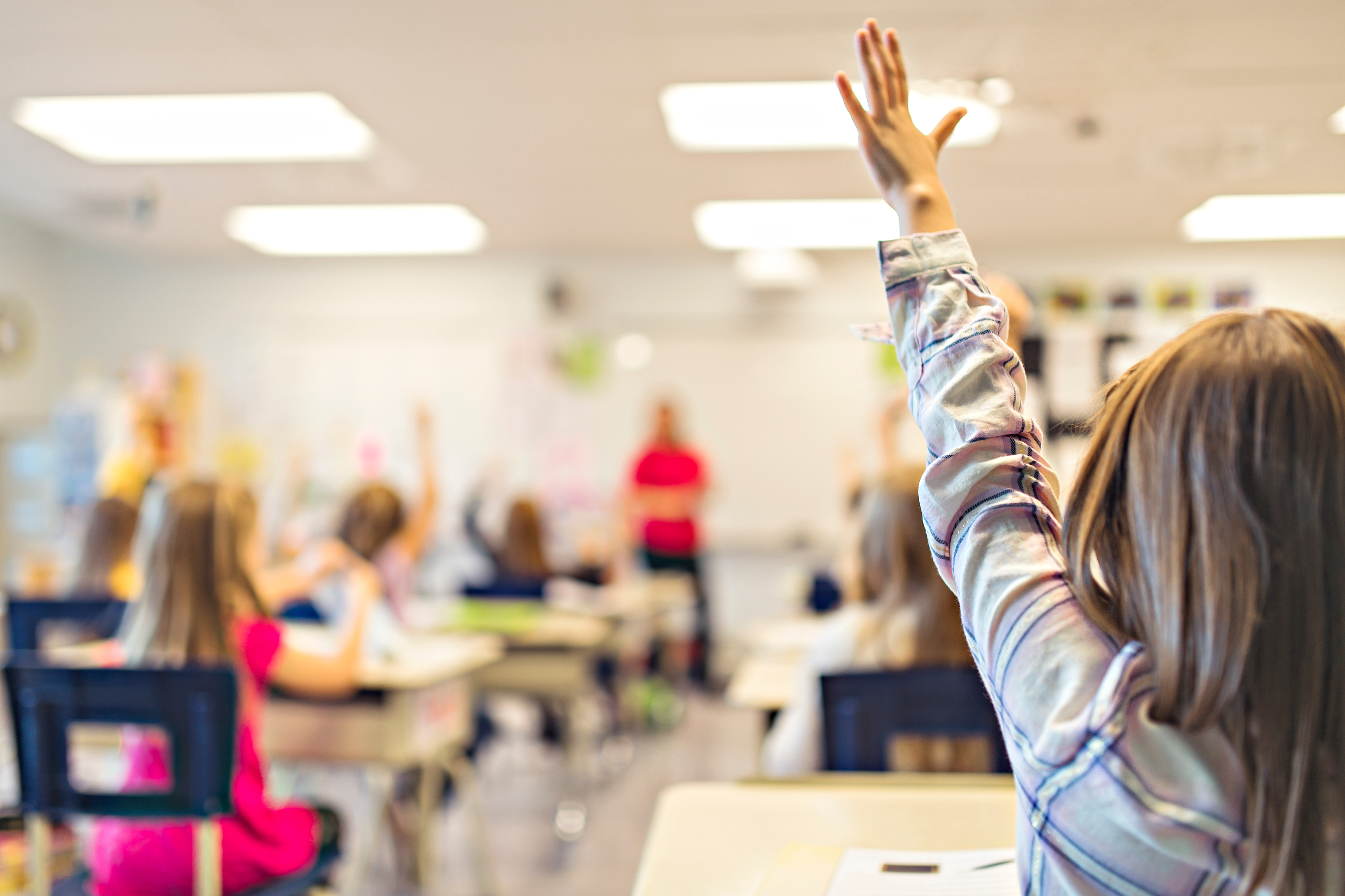 student raising her hand in classroom