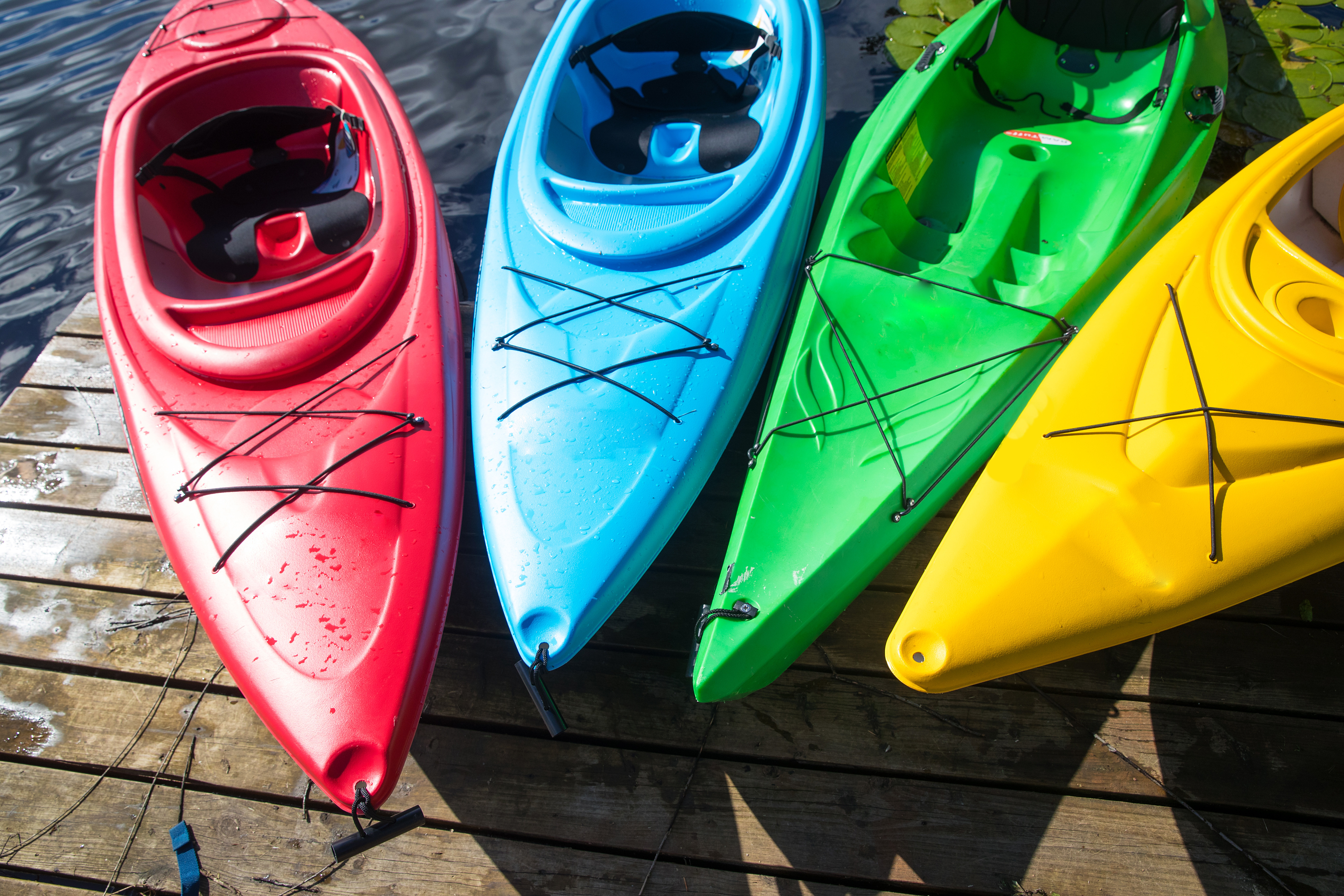 4 colorful kayaks next to a wooden dock