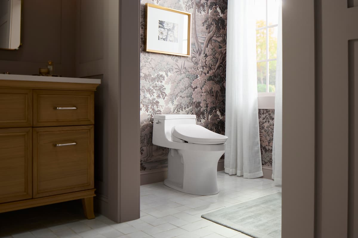 Kohler bidet toilet seat in a bathroom with pretty wallpaper and drapery