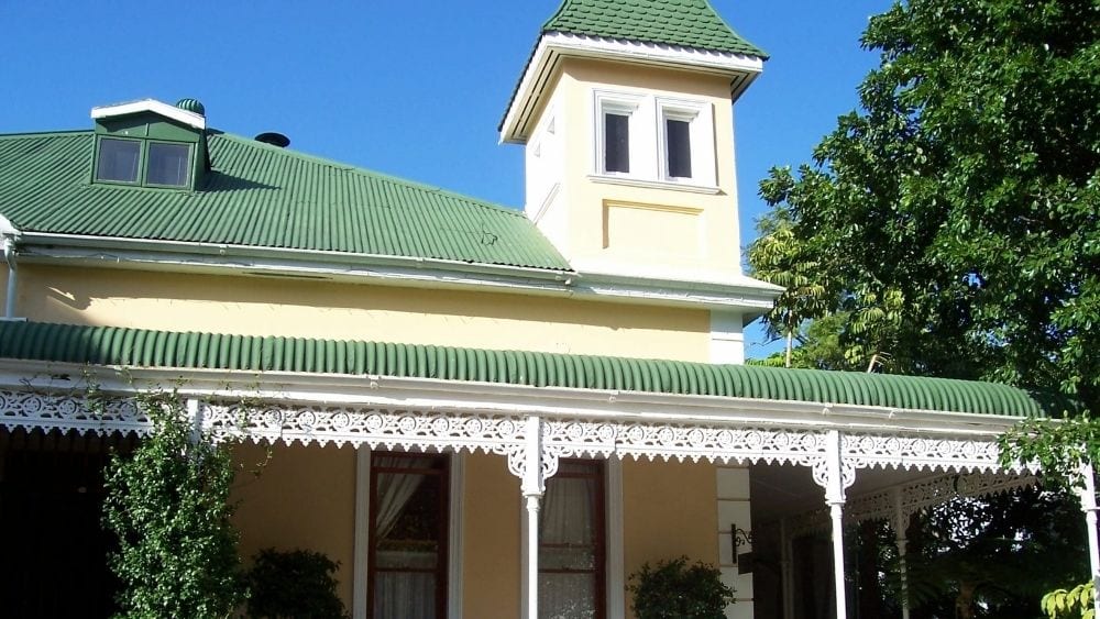 Victorian-style house with yellow siding and a green metal roof and a turret.