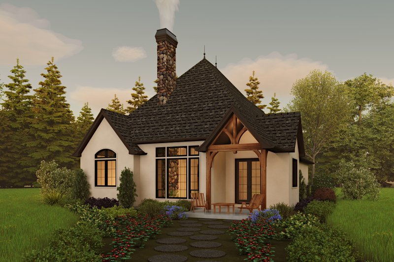 Small, cottage style home with black roof and white exterior, set in the woods