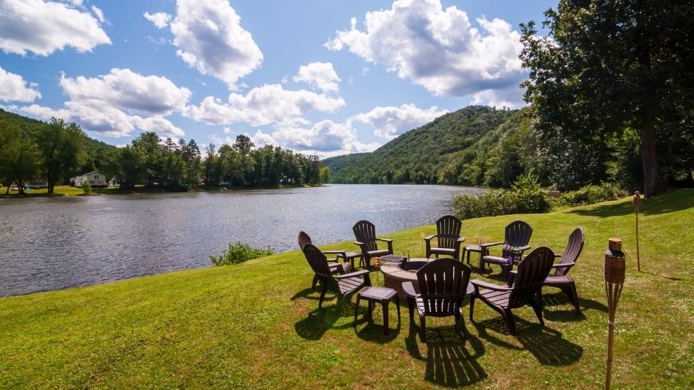 Chairs gathered on the bank of the Allegheny River on a sunny day.