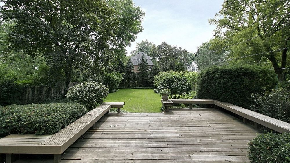 Deck with benches leading into a backyard.