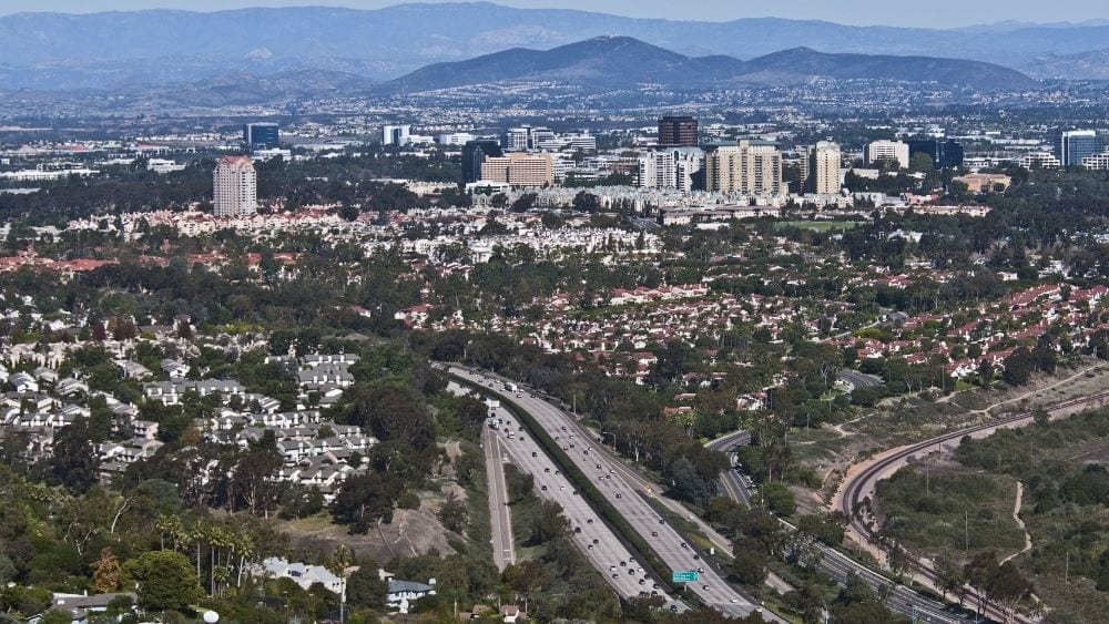 A sprawling suburban city with mountains in the background.