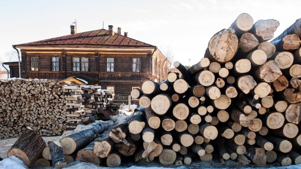 A large wood house with piles of lumber in the yard.