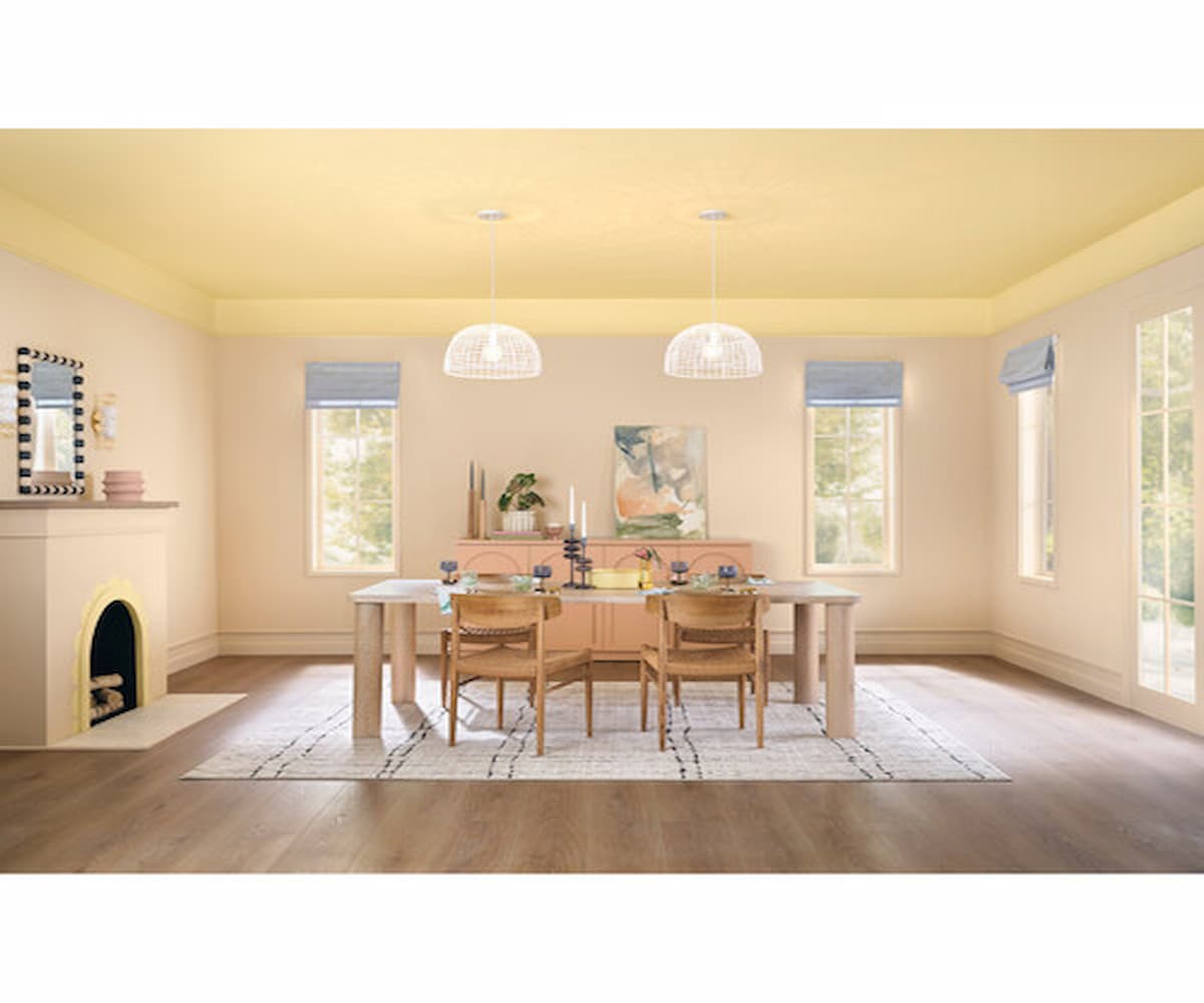 Dutch Boy's Paint Color of the Year Melodious Ivory, shown here in a dining room with lots of windows and a white fireplace.