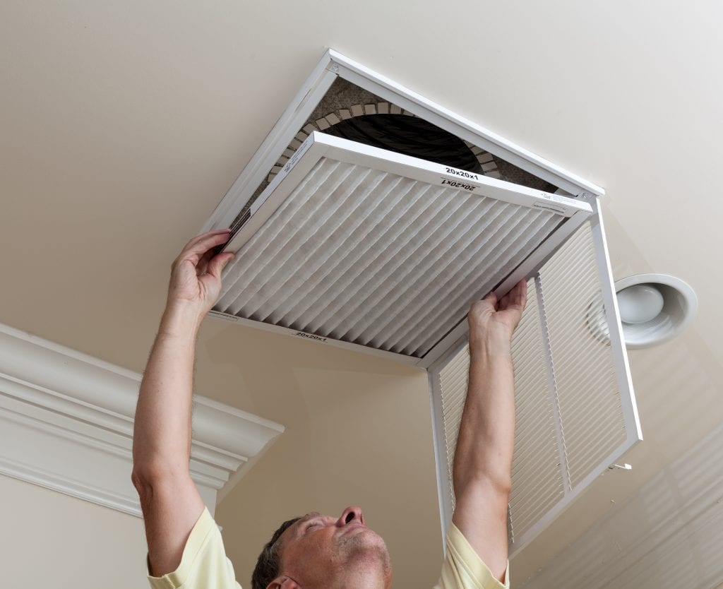 A man changes the air filter in his home.