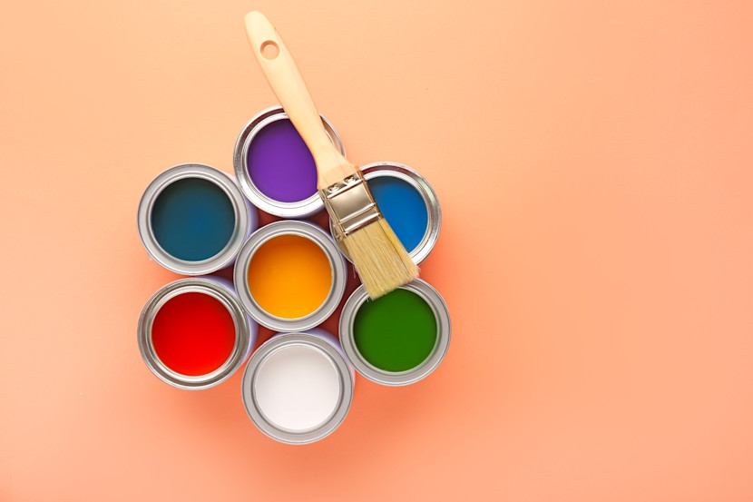 Paint cans in a circle, with a paintbrush lying across the top