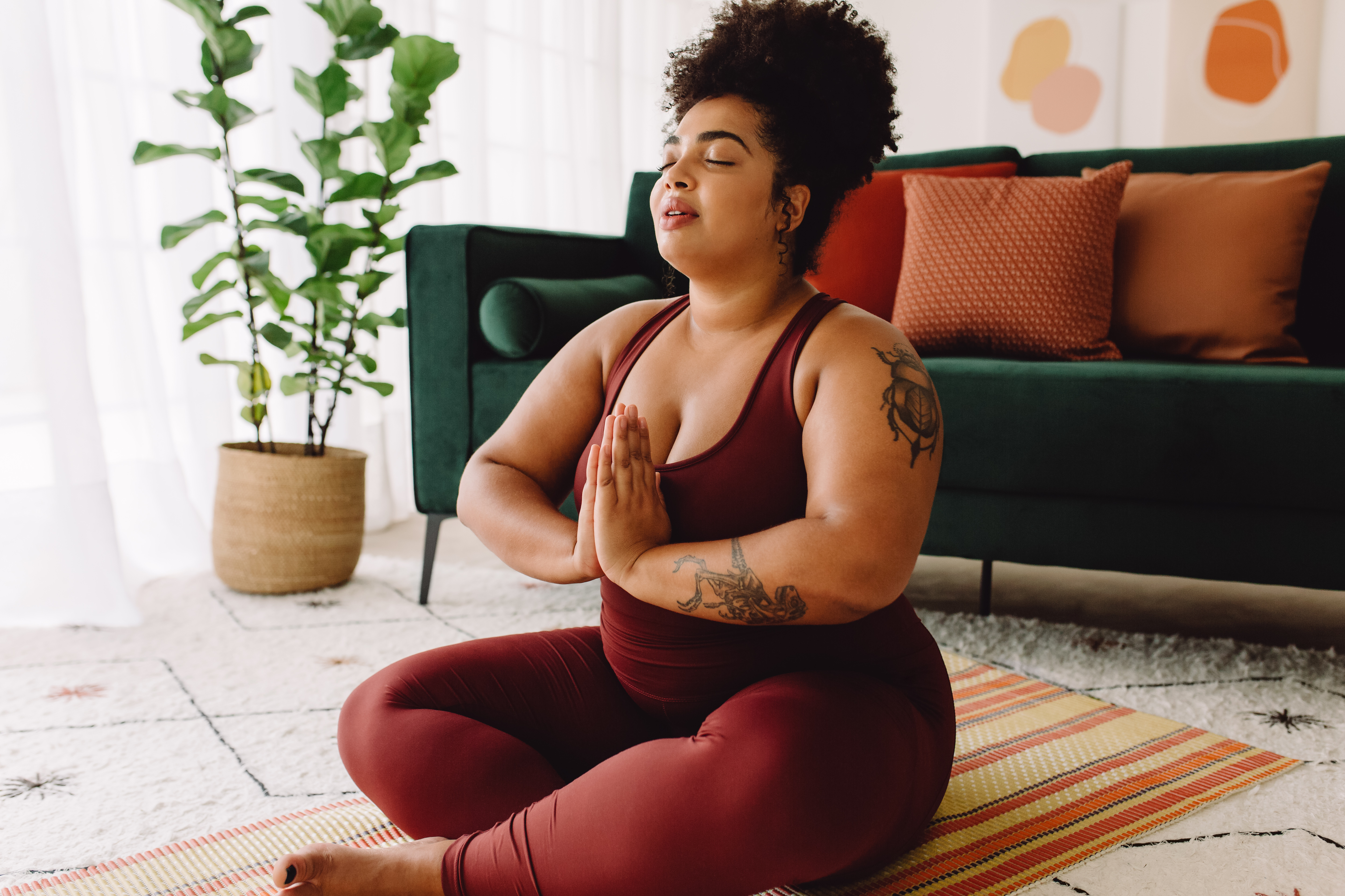 A BIPOC woman meditating in her home