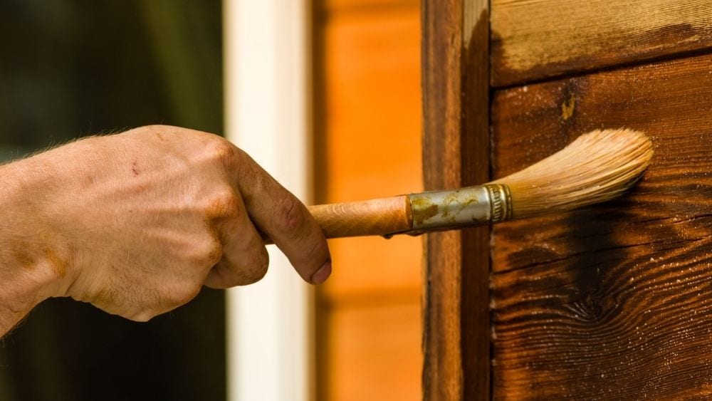 Close-up of someone painting on wood finish.