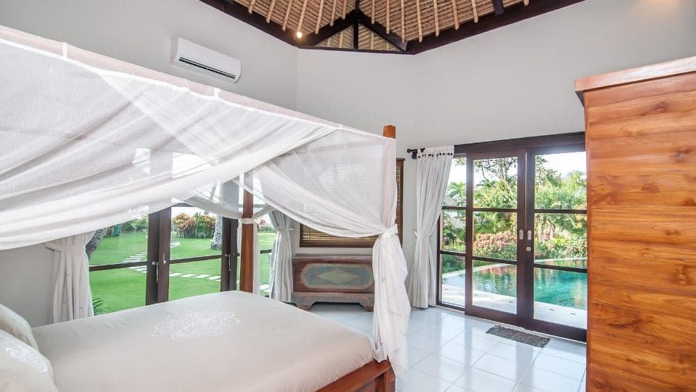 Luxury bedroom with two sets of double doors leading to a backyard.