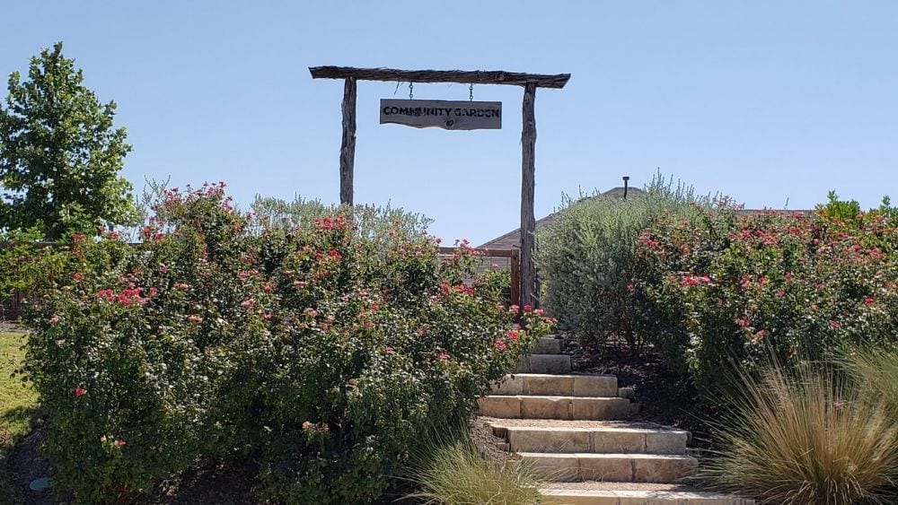 A sign reading “Community Garden” over a lush greenspace.