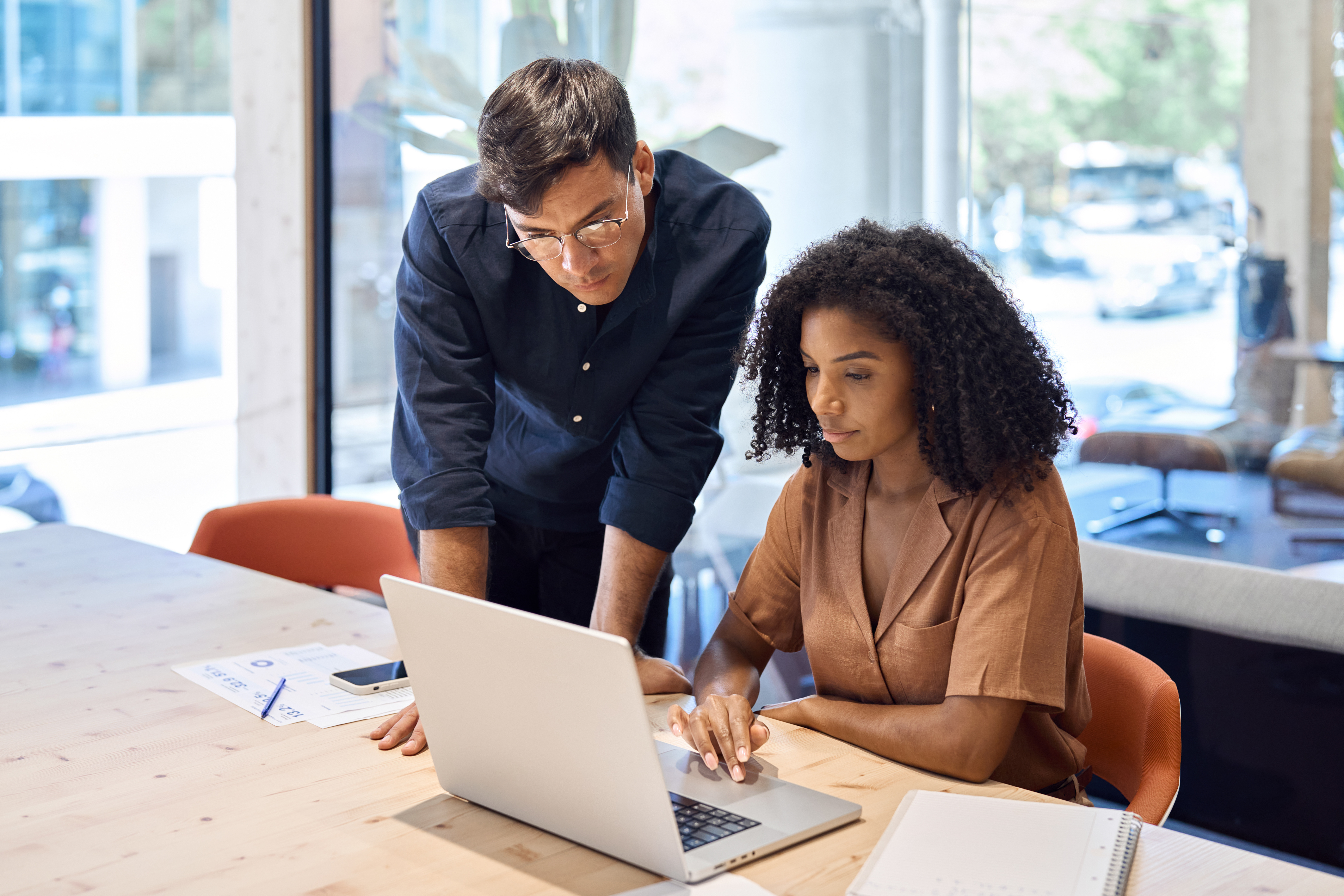 A male and female overlooking a computer in the office
