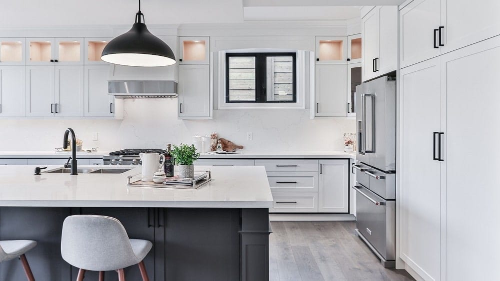 White kitchen with large island, sleek countertops, and pendant light