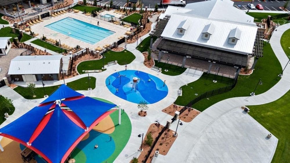 Aerial view of an amenity center in a neighborhood with two pools, a community center, and a pavilion.