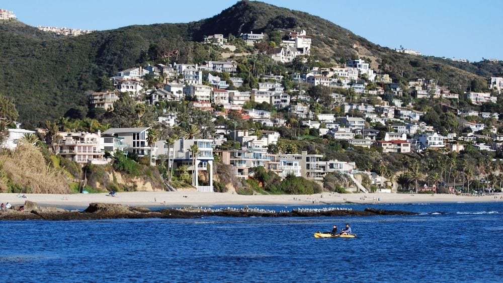 View from the water of modern homes built into a mountainside.