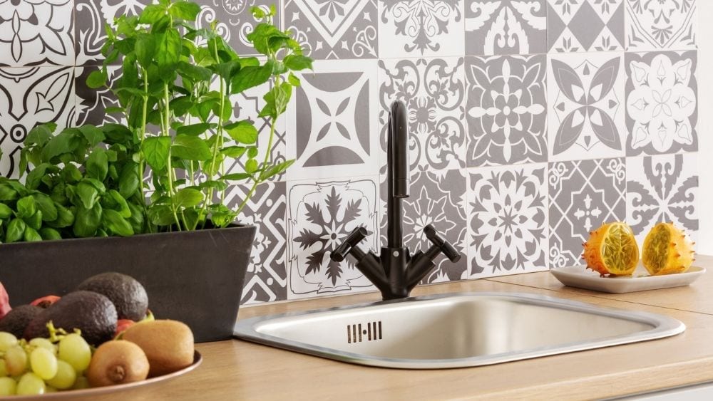 Simple inset kitchen sink with wood countertops and a patterned backsplash.