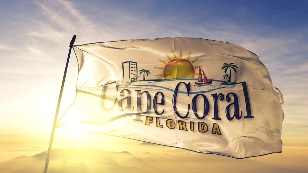A white flag reading “Cape Coral, Florida” with the sun in the background.