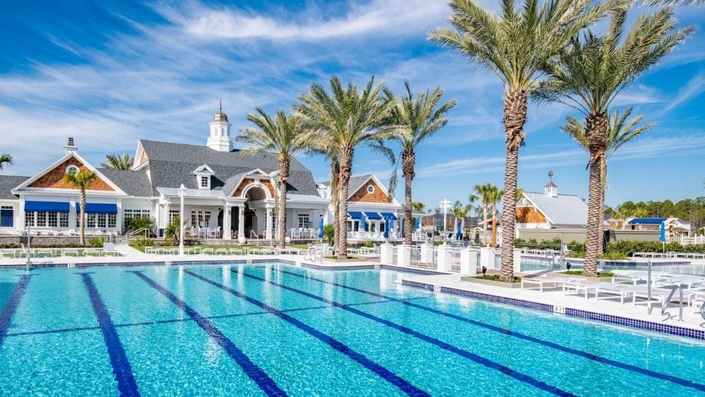 Large community pool lined with palm trees and a resort-style building.
