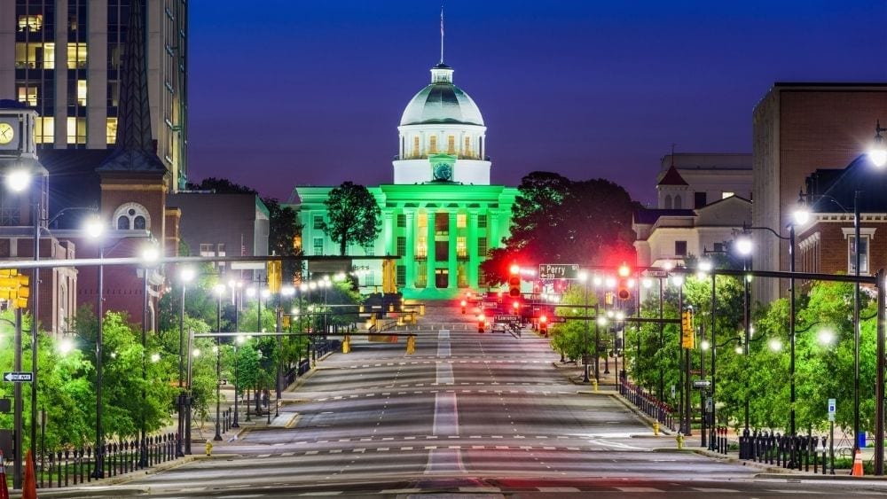 The view from the middle of the street, looking toward a capital building with a domed white roof.