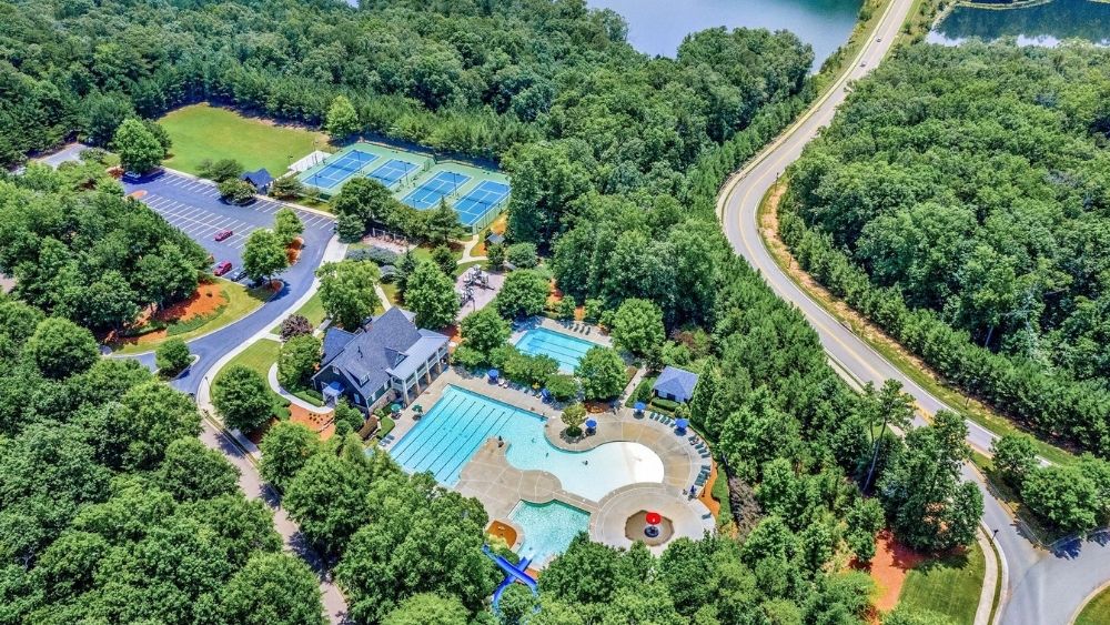 Aerial view of a community center with a pool and recreational center, surrounded by trees.
