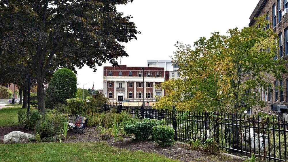 A historic building standing between trees in a city park.