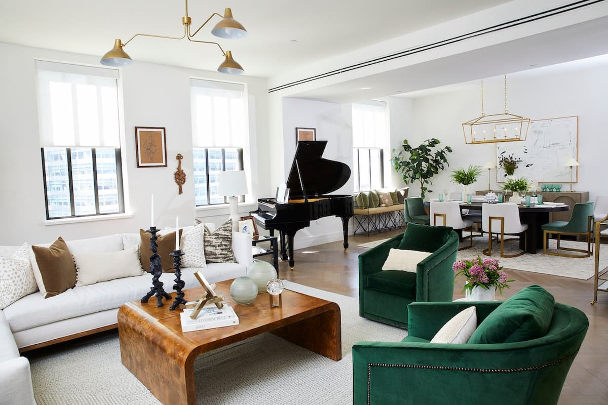 living room in quiet luxury style, with sofa set, green armchairs and baby grand piano, leading to an open dining area