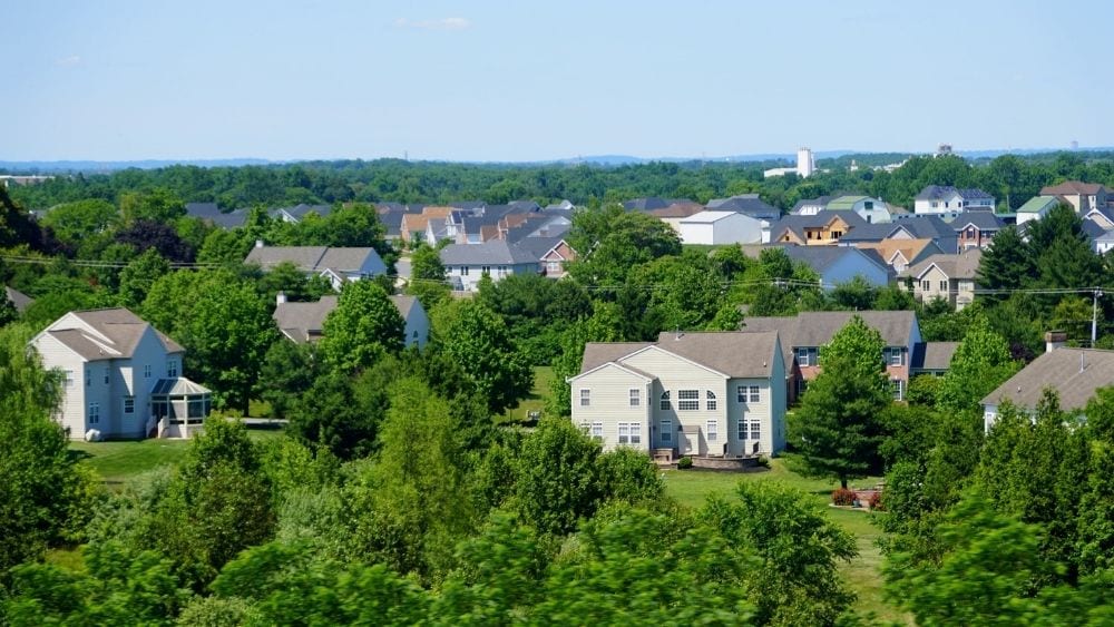 View looking out over a suburb with lots of well-maintained houses, trees, and green space.