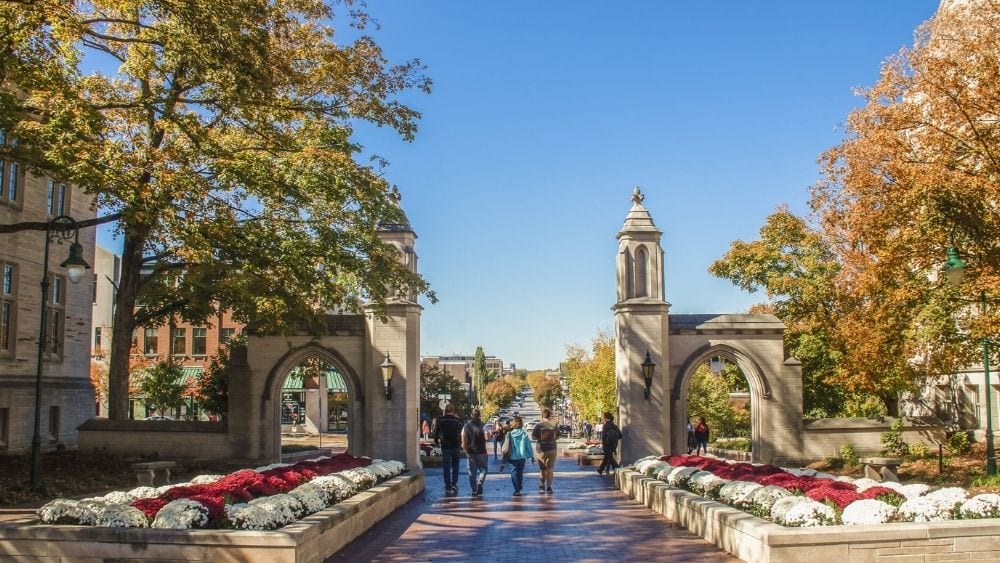 Entrance to Indiana University Bloomington. A stone structure lined by trees in autumn.