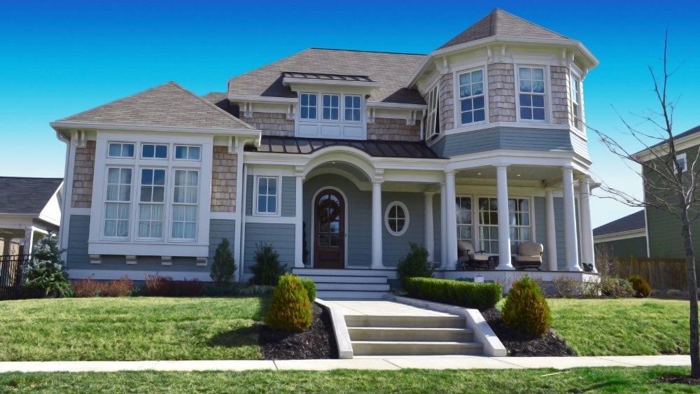 A lovely two-story home with a partial wrap-around porch in a suburban area.