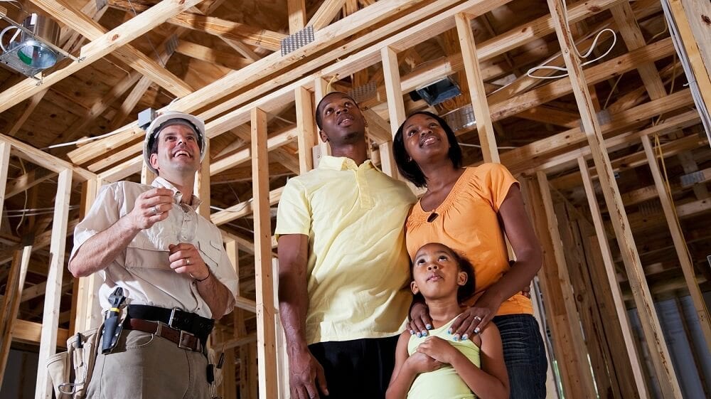 Family standing in house under construction talking with builder