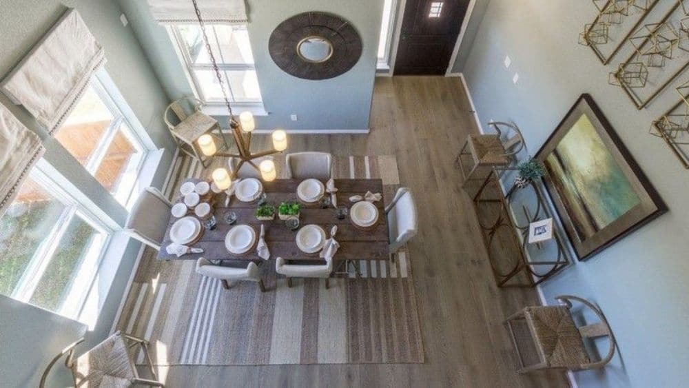 View from above of a dining room with a chandelier and large windows.