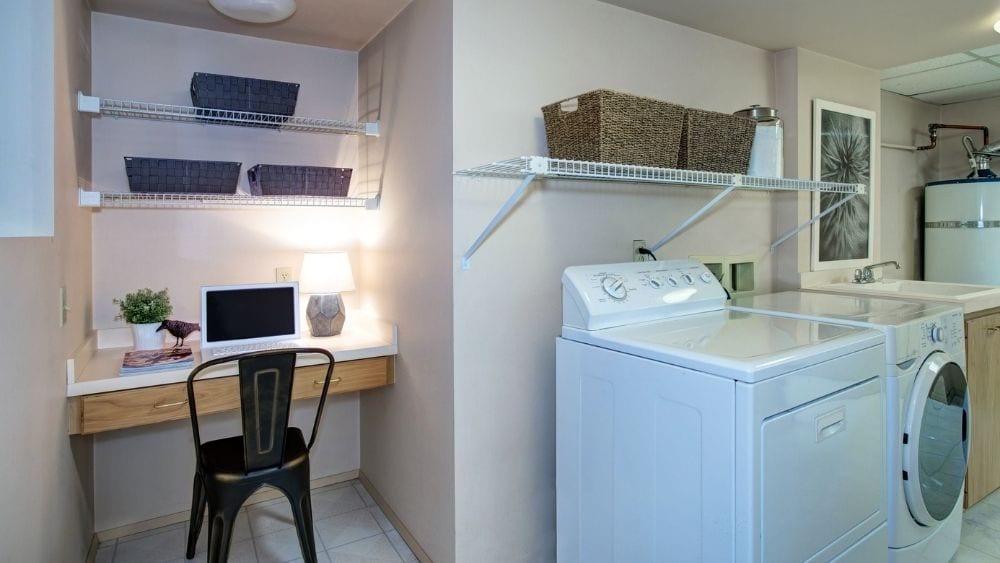 Desk in an alcove next to a washer and dryer.