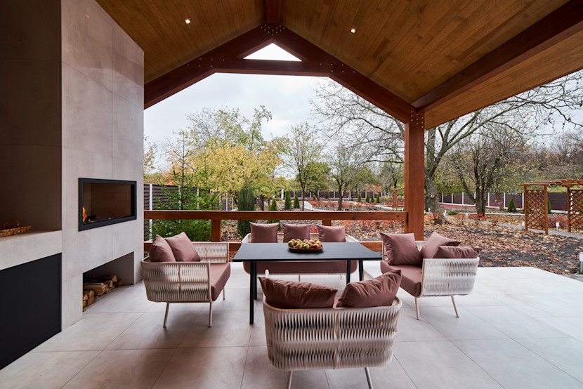 Outdoor living room with conversation set, outdoor fireplace and peaked wooden covered porch