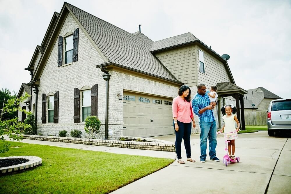 Family of four standing outside their home on the driveway