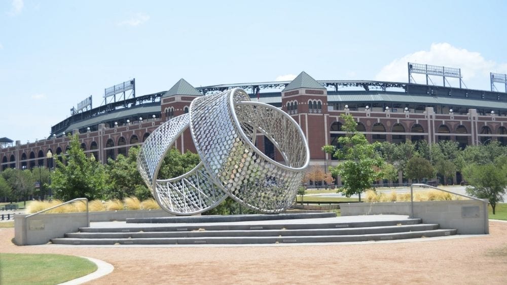 A modern metal sculpture in front of a sports stadium.
