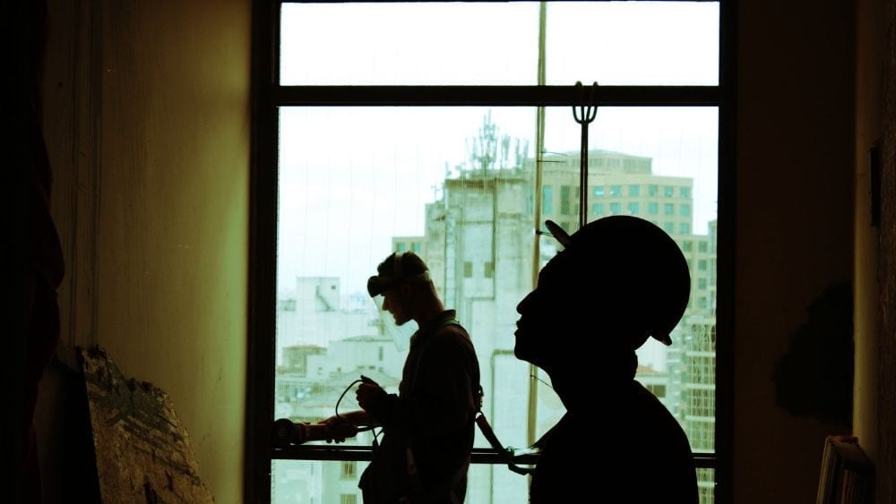 two builders working on an infill property in front of a window